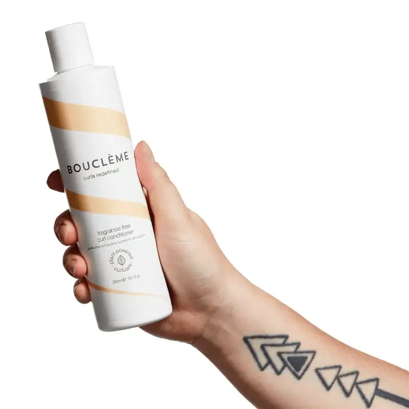 Hand holding Bouclème fragrance-free curl conditioner for defined, healthy curls