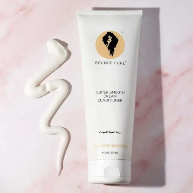 Bounce Curl Super Smooth Cream Conditioner for curly hair, shown with swirled product on pink marble background