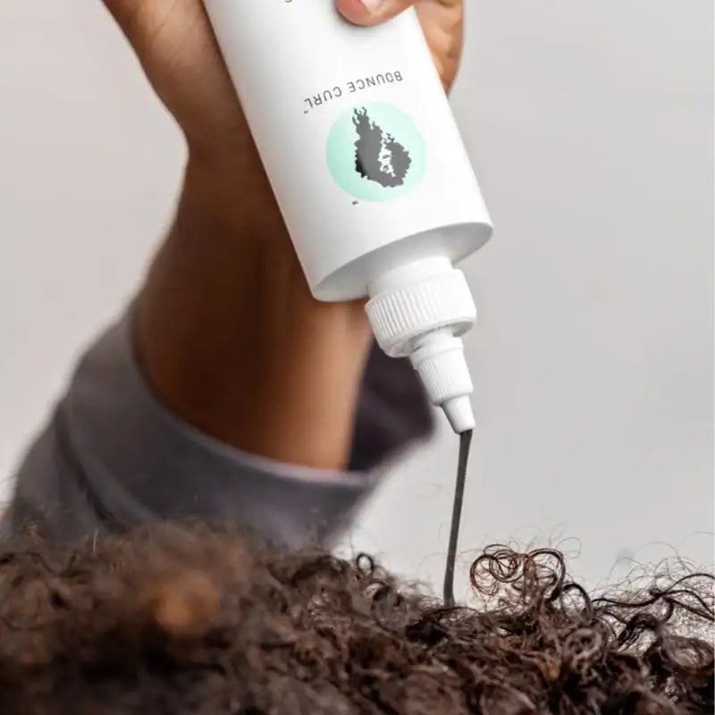 Applying Bounce Curl product to defined curly hair for hydration and definition