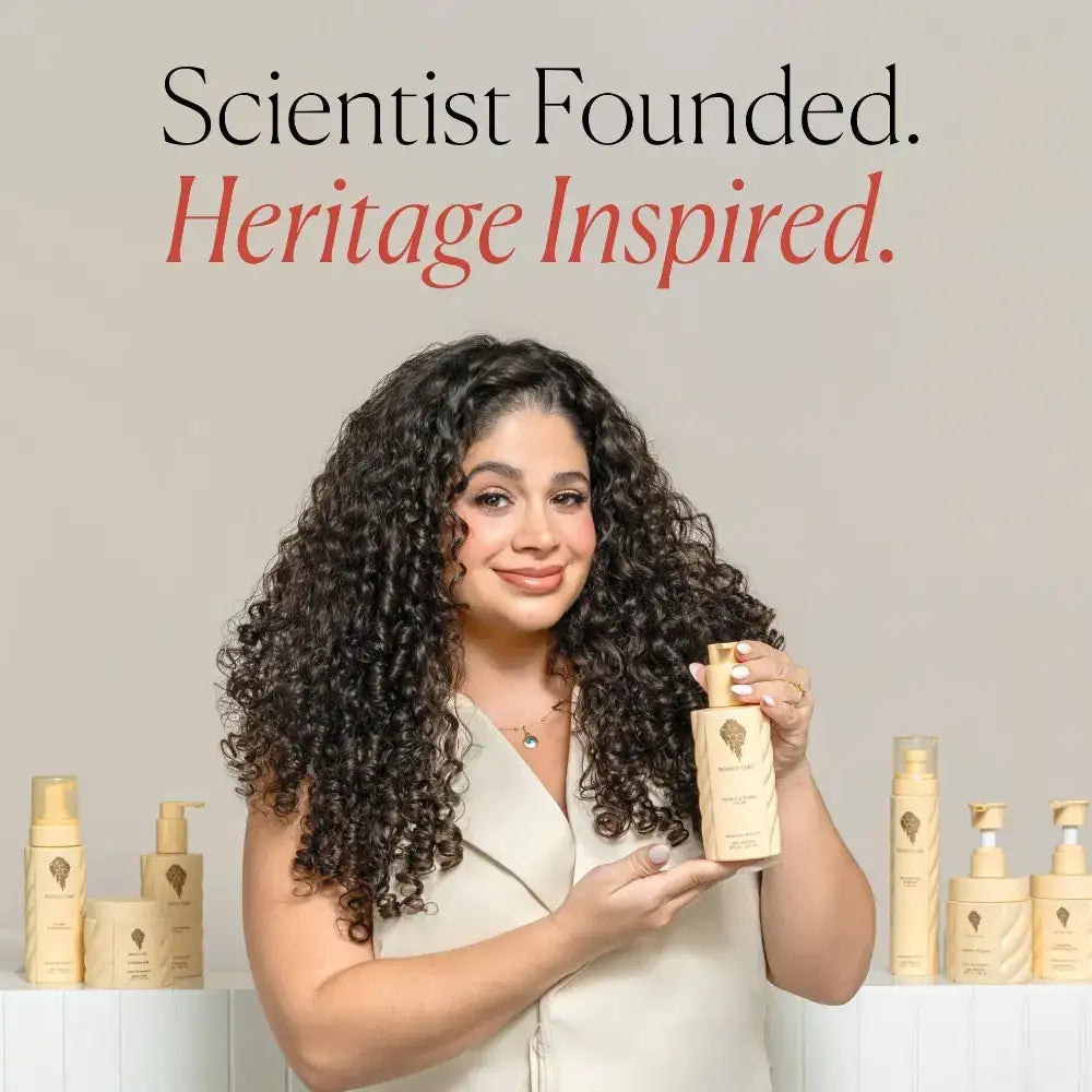 Curly hair model holding heritage-inspired curl care product, surrounded by matching bottles for defined, healthy curls.