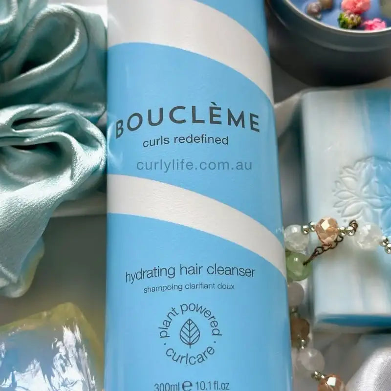 Bouclème hydrating hair cleanser for curly hair, plant-powered curl care with silk bonnet nearby