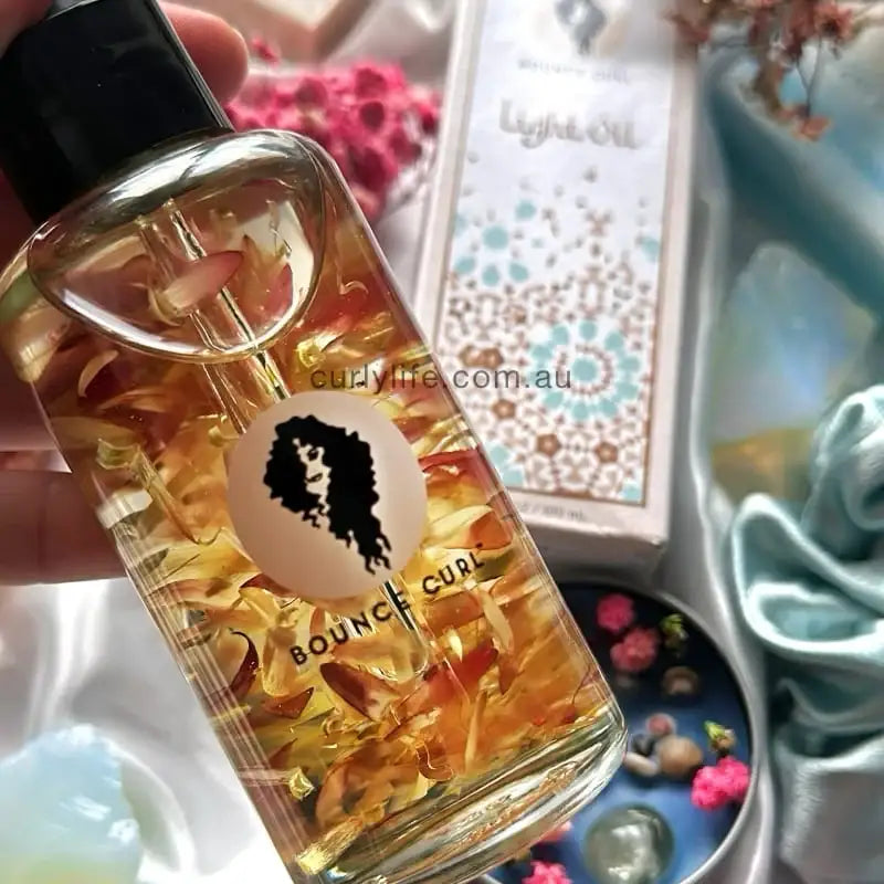 Bounce Curl Light Oil with flower petals, curly hair care product for definition and shine